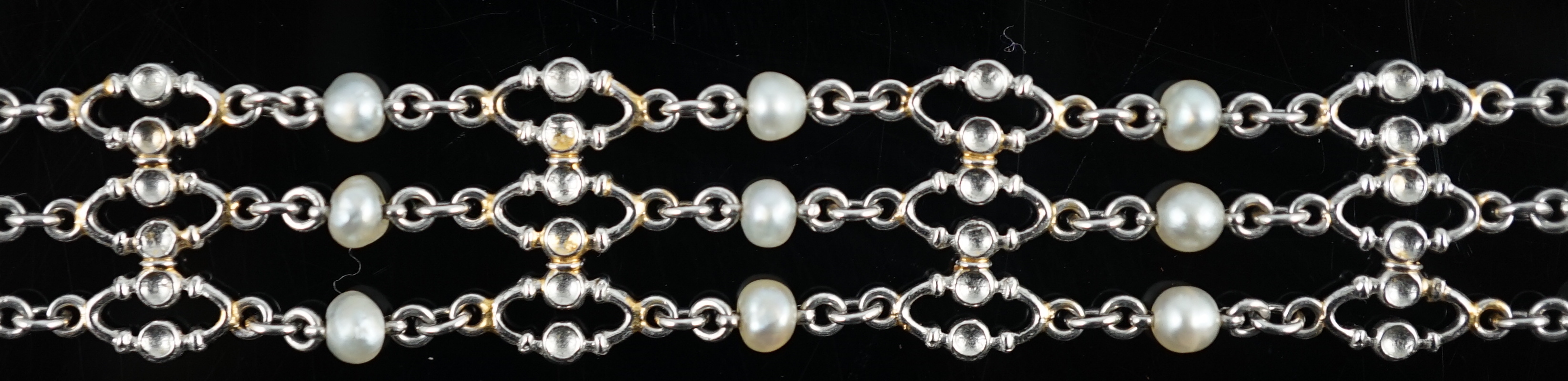 An early to mid 20th century white gold and seed pearl set three row chain link bracelet